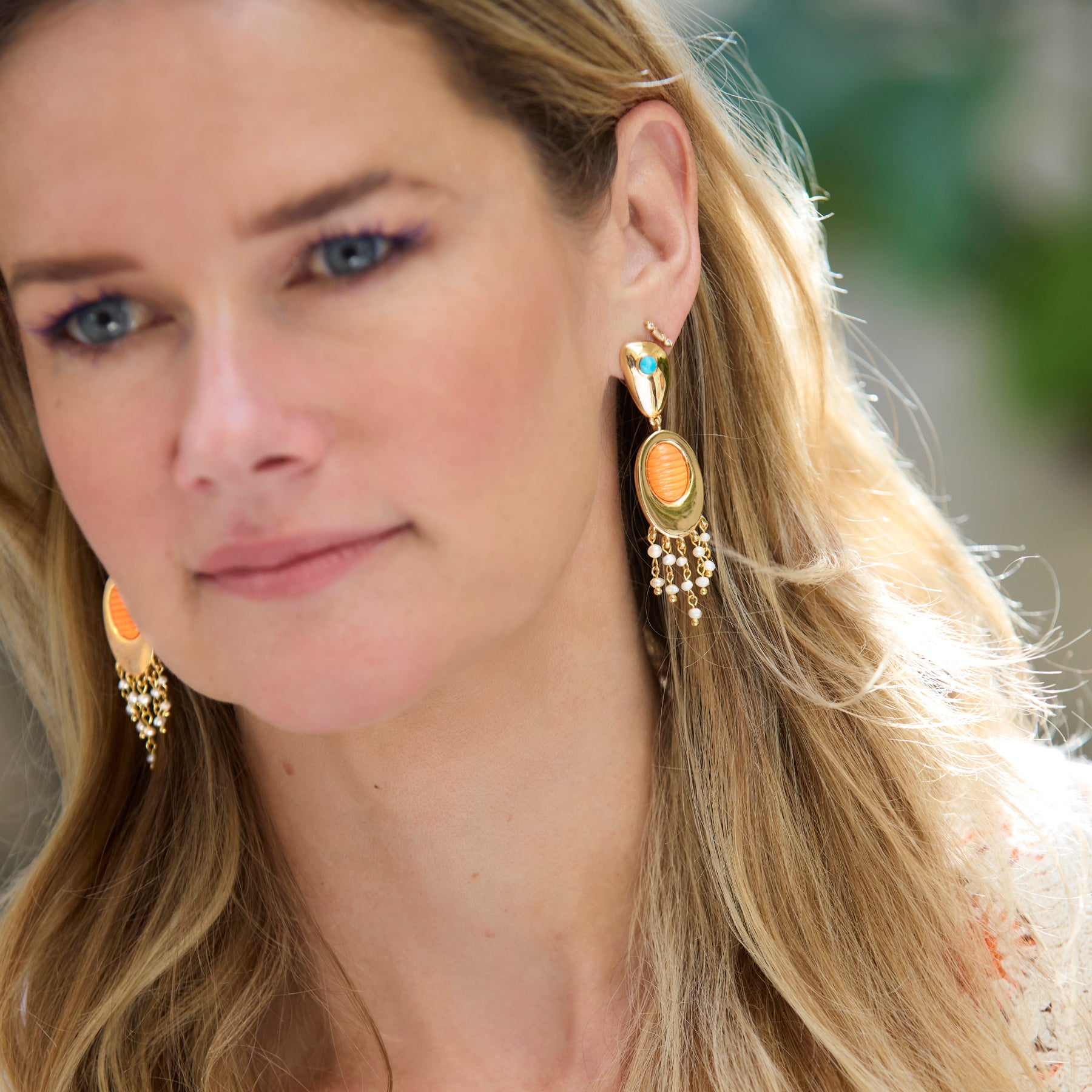 Close-up of a woman wearing gold earrings with a blurred background