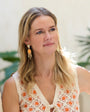 Model wearing gold drop earrings with white and orange crochet dress