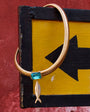 Necklace with a blue gemstone on a yellow and black sign against a red wall.