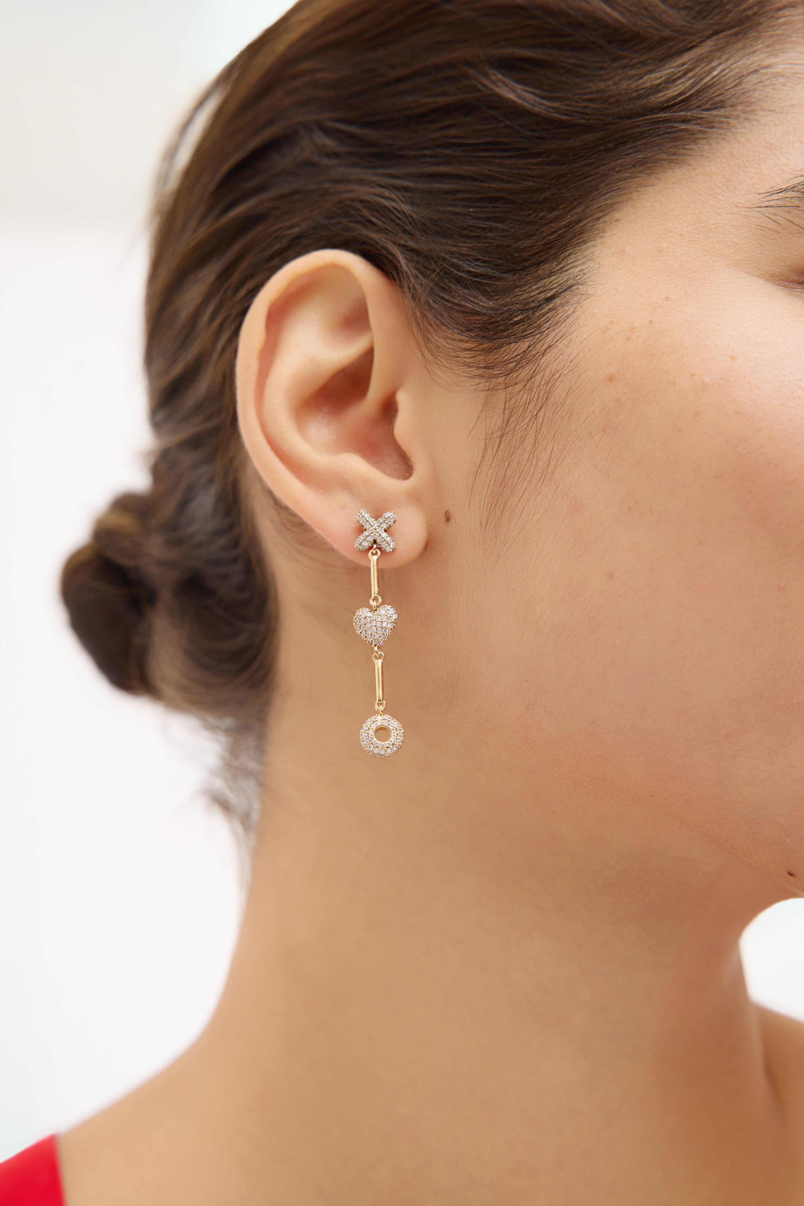 Close-up of a woman wearing a gold earring with a white background