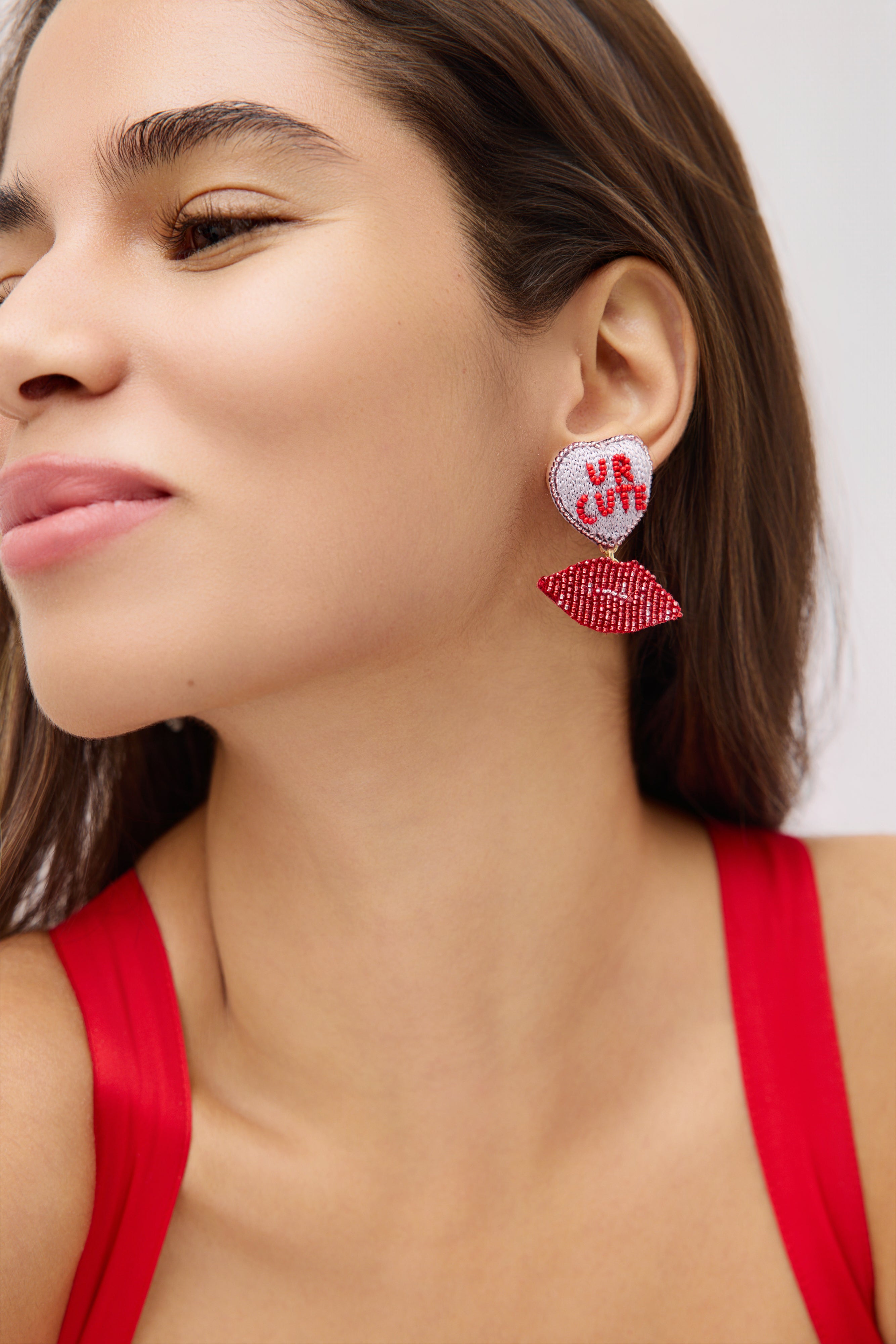 Close-up of a woman wearing red earrings with heart designs.