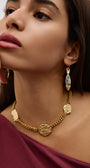 Woman wearing a gold necklace and earrings on a plain background