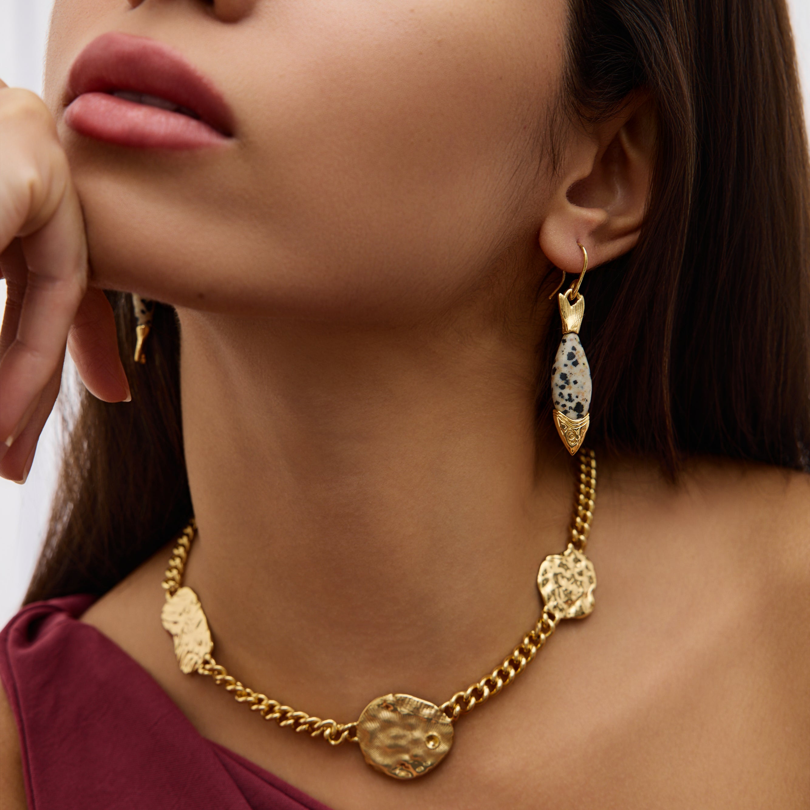 Woman wearing a gold necklace and earrings on a plain background