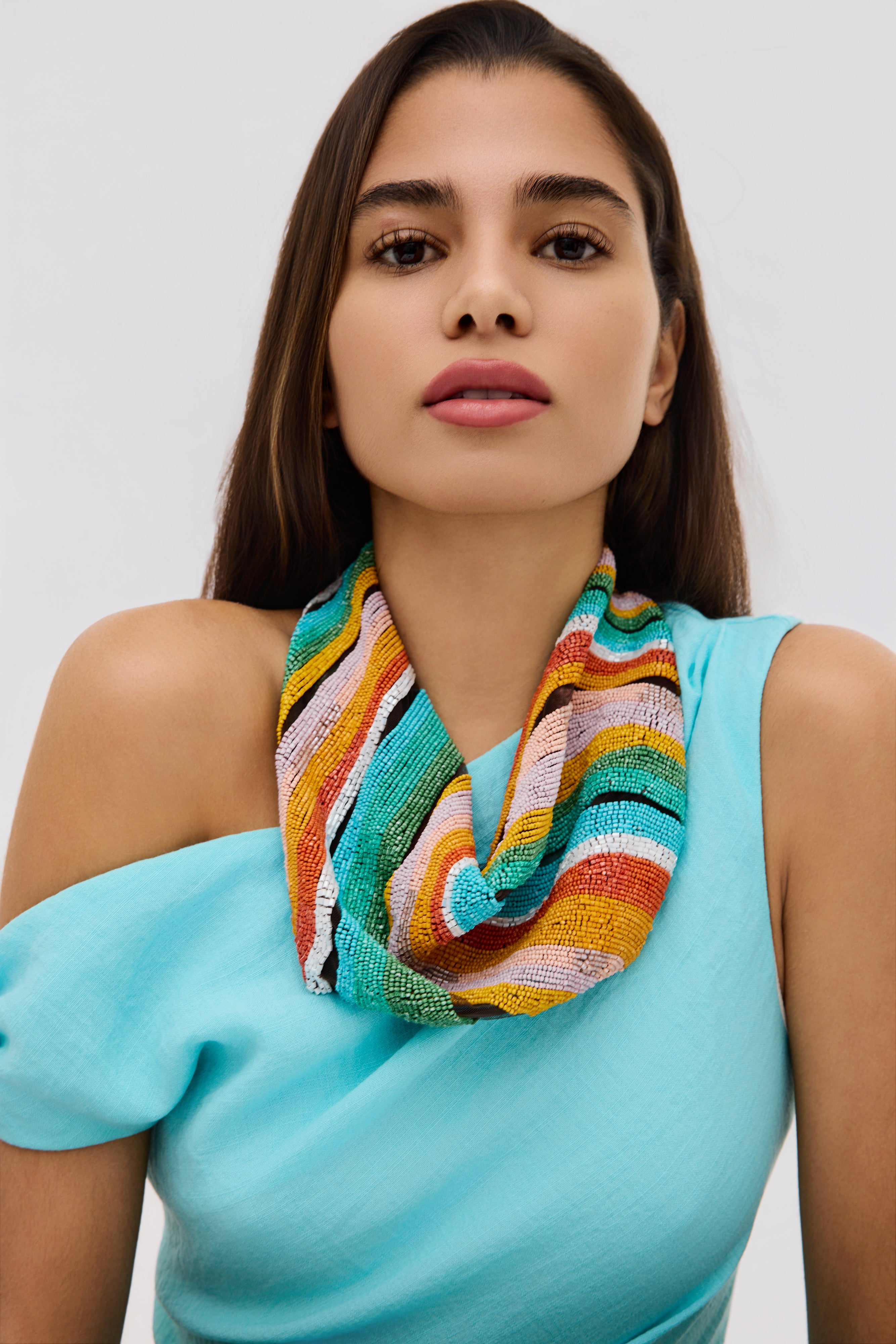 Woman wearing a colorful scarf with a plain background