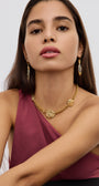 Woman wearing a gold necklace and earrings against a white background