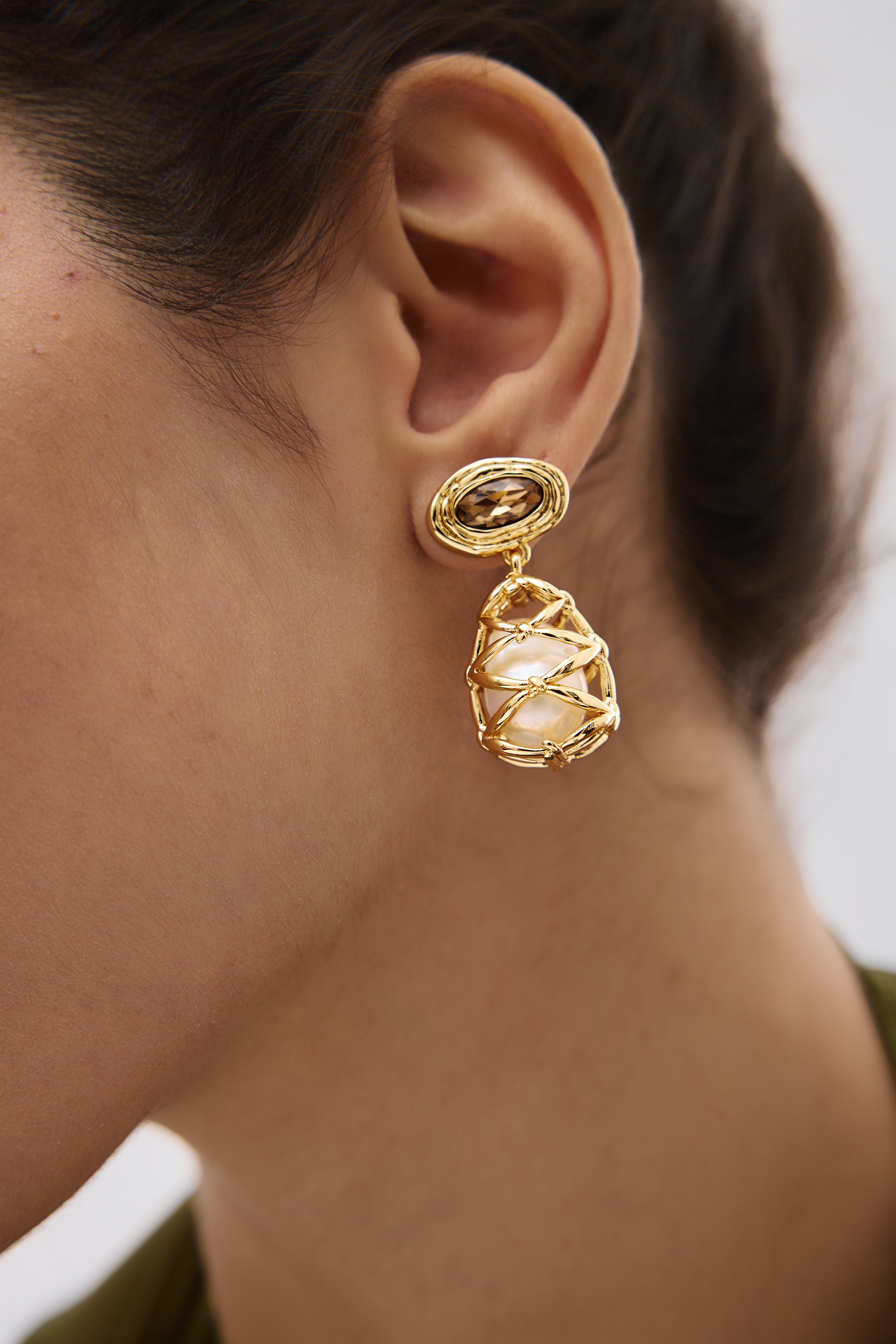 Gold earring worn by a person with a blurred background