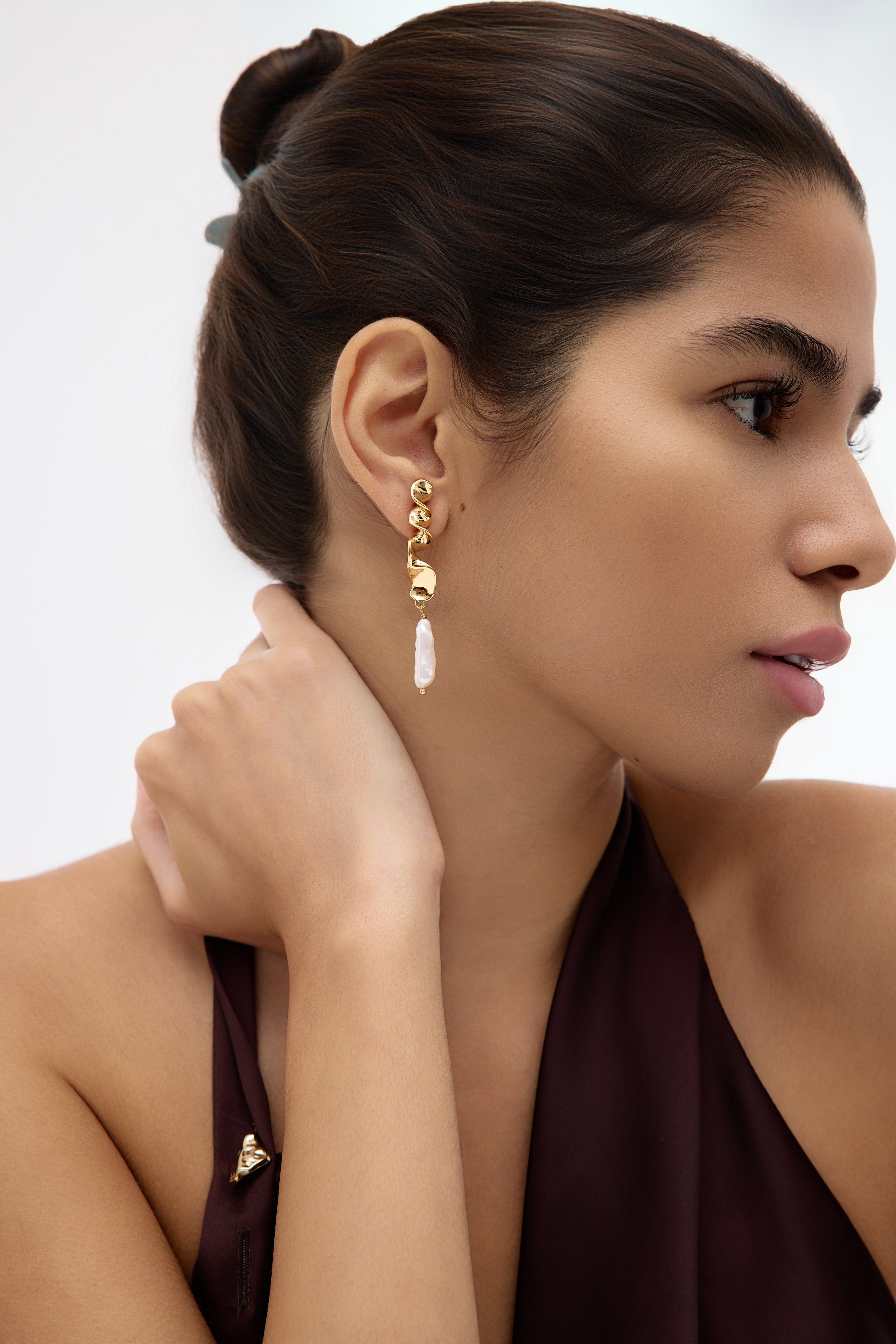 Woman wearing gold earrings with a neutral background