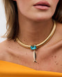 woman wearing a gold neckace with a gold fish and blue crystal wearing an orange shirt