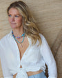 Woman wearing a white top with a beaded necklace against wooden background