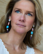 Woman wearing colorful earrings with a neutral background