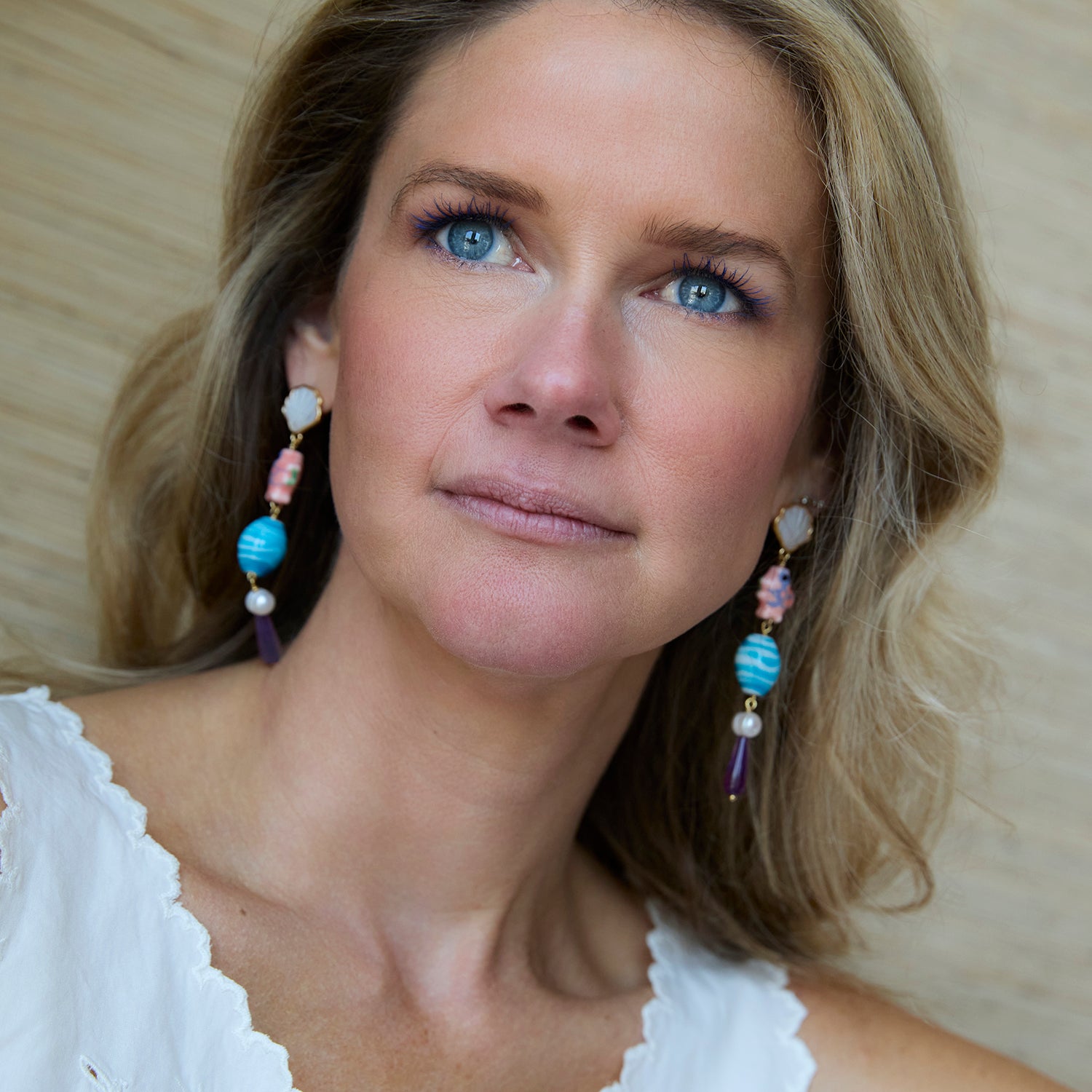 Woman wearing colorful earrings with a neutral background