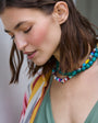 Woman wearing a colorful beaded necklace with a blurred background