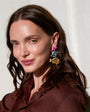 Woman wearing colorful earrings against a neutral background