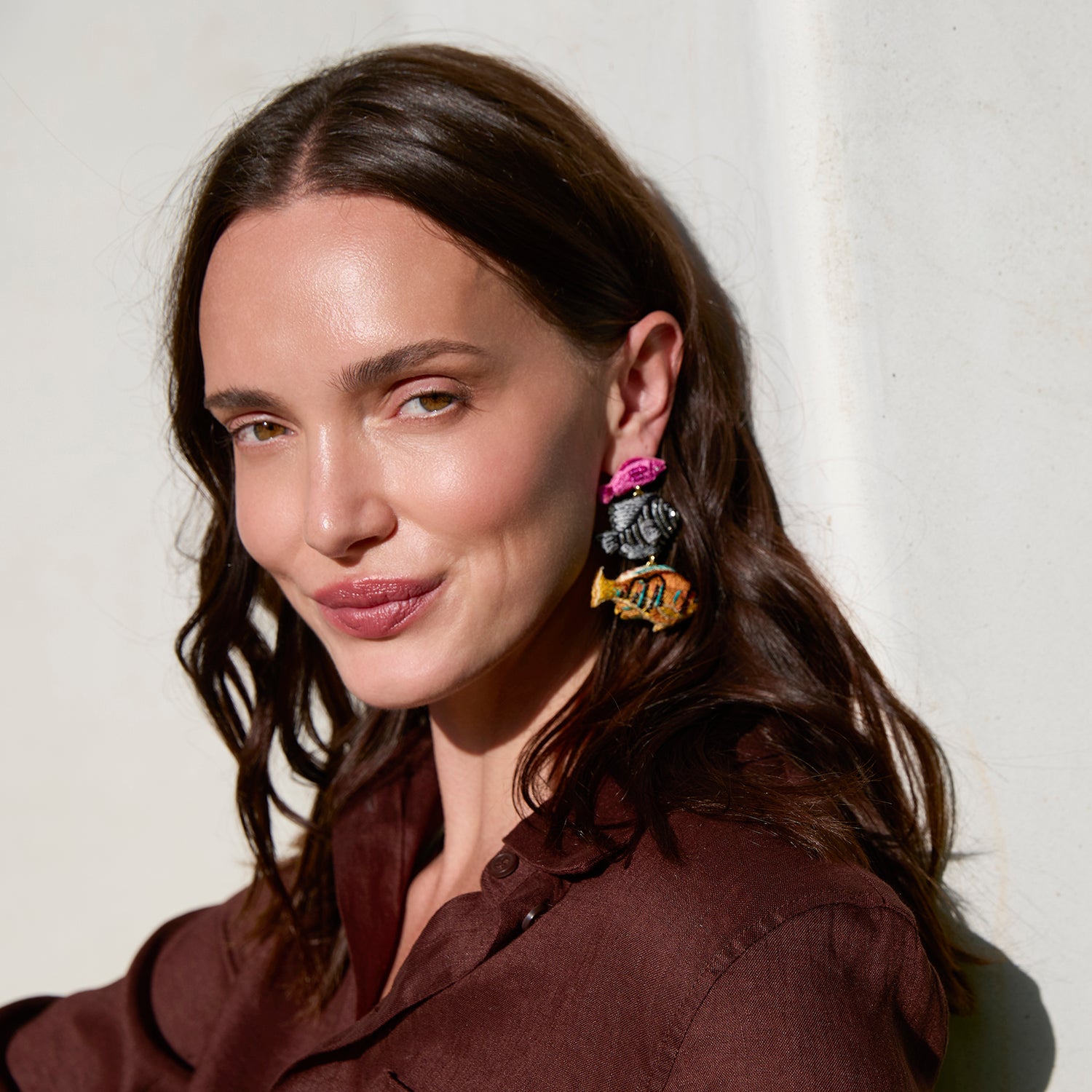 Woman wearing colorful earrings against a neutral background