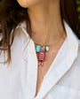 Necklace with colorful charms worn by a person in a white shirt.