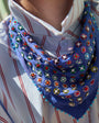 Model wearing blue and sequin emboidered scarf around her neck with a striped shirt 