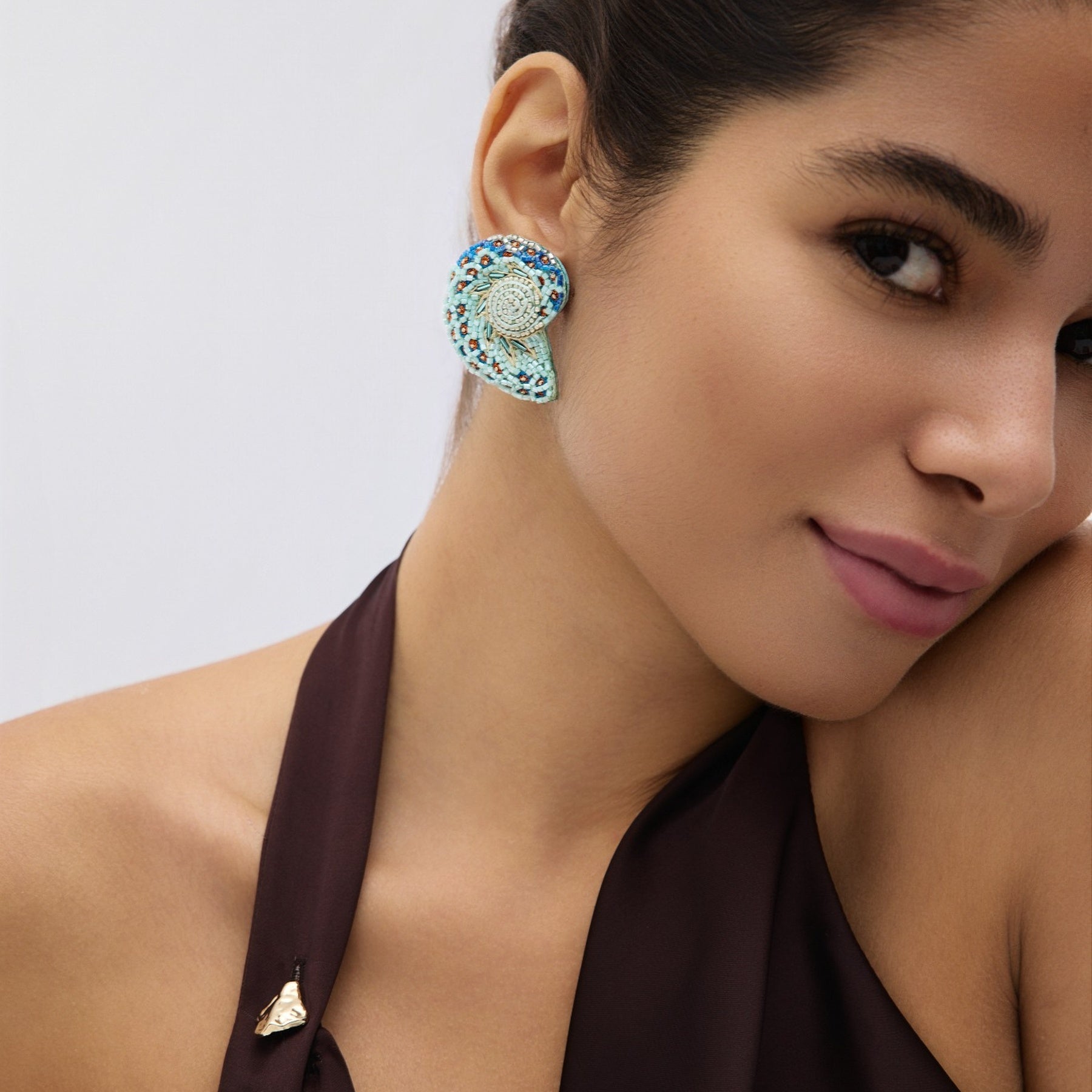 Close-up of a woman wearing a decorative earring with a neutral background