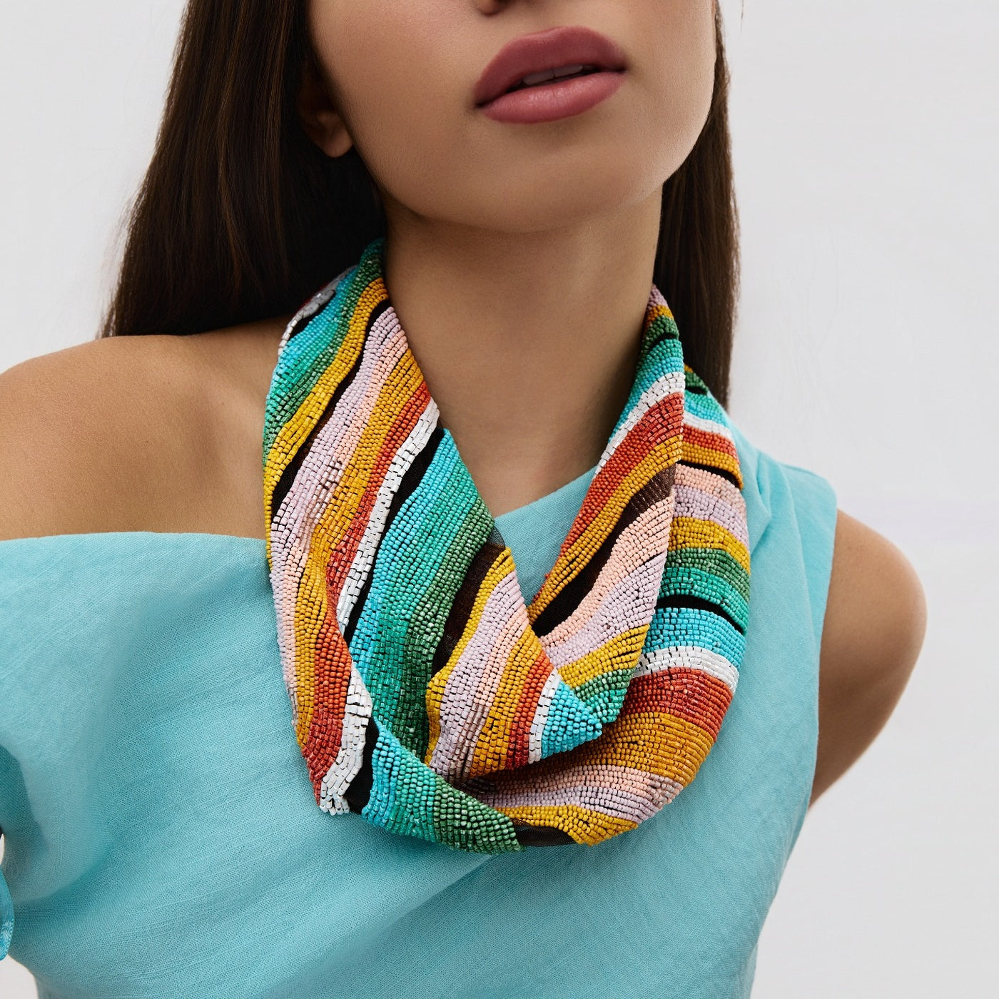 Woman wearing a colorful beaded scarf against a white background