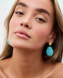 Woman wearing turquoise earrings with a plain background