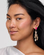 Woman wearing a pink gemstone earring with a white background