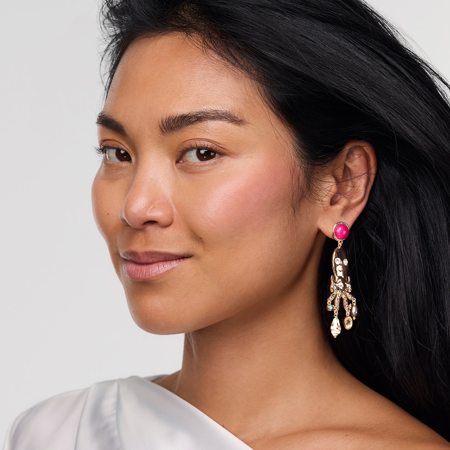 Woman wearing a pink gemstone earring with a white background