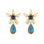 A pair of gold flower-shaped drop earrings featuring a round dark blue cabochon stone at the center and a teardrop-shaped turquoise stone hanging below, set against a plain white background.