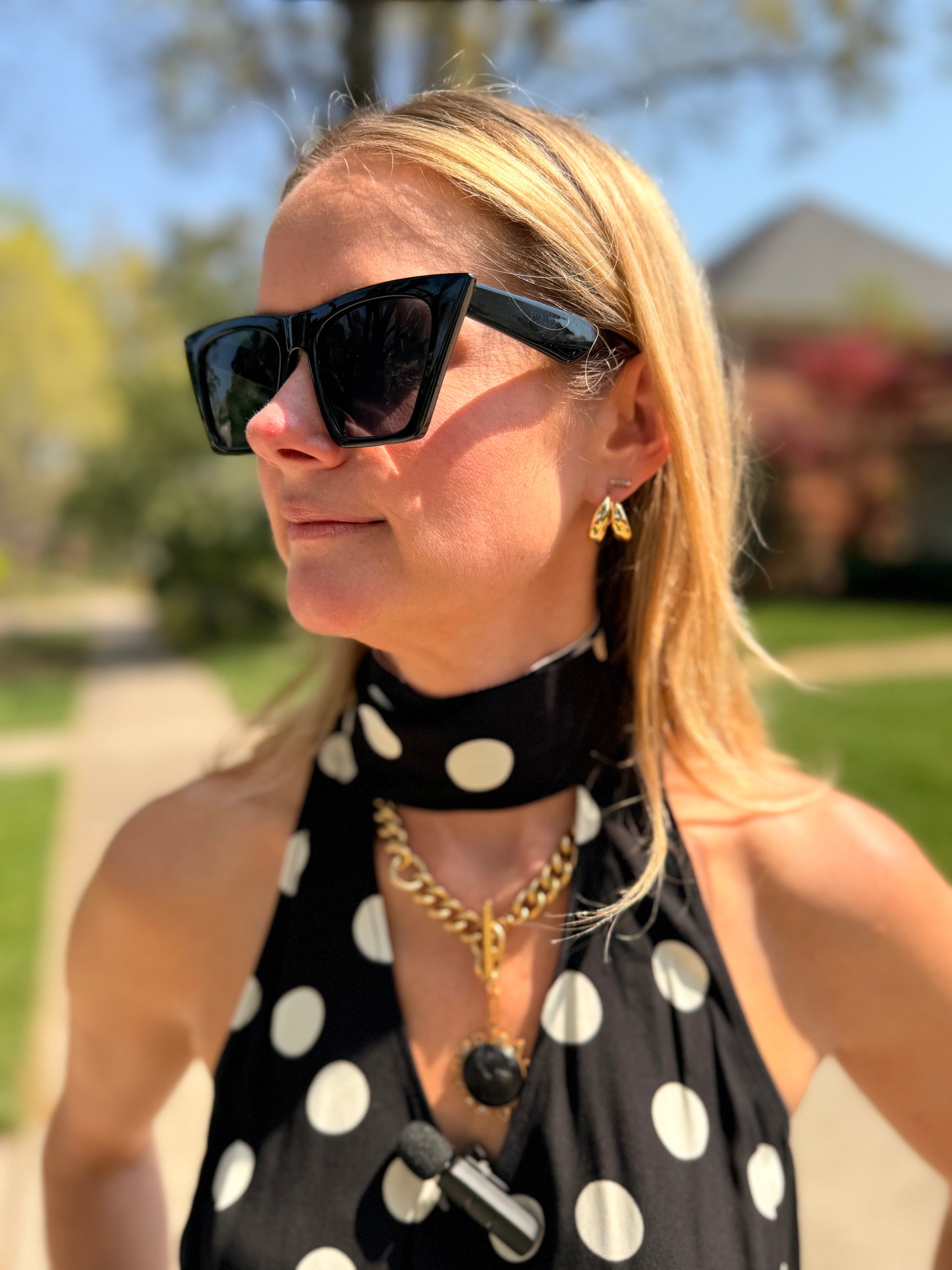 Maggie wearing gold hoop earrings in a polka dot black and white top 