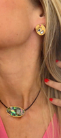Close-up of a person wearing gold earrings and a necklace with a colorful pendant.