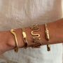 Model wearing gold cuff against beige background