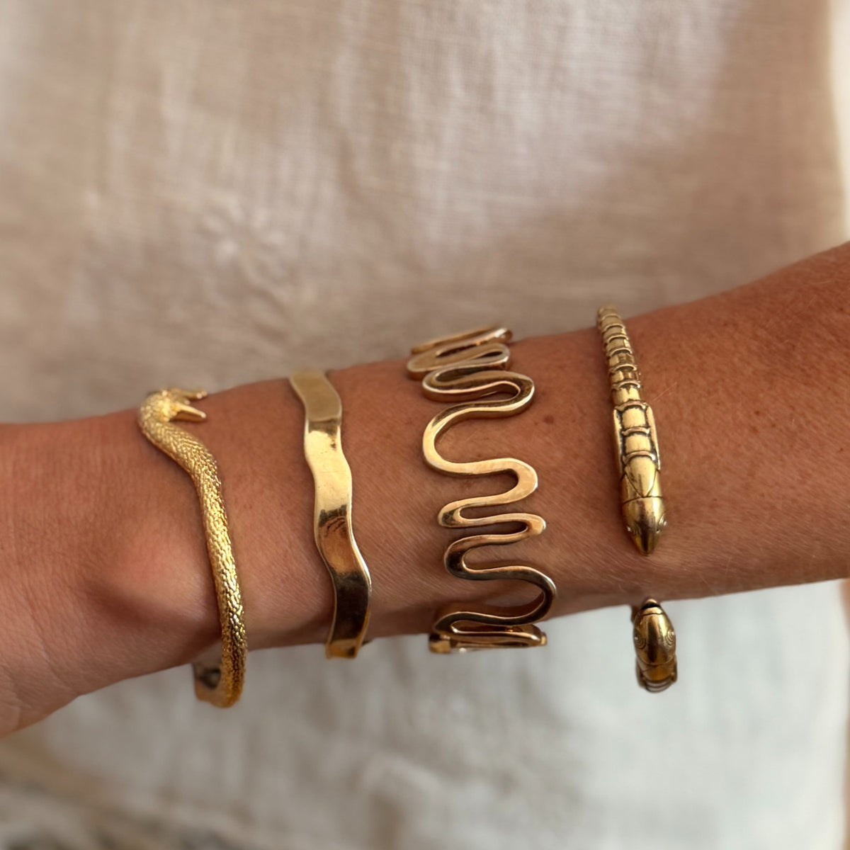 Model wearing gold cuff against beige background