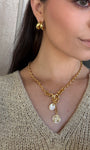 Woman wearing a gold necklace with pendant, close-up of neck and chest area.