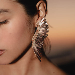 Metallic Rose Gold Wing Earrings Styled on Model at the Beach During Sunset