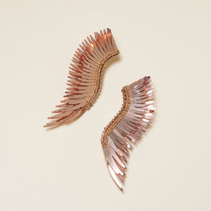 Metallic Rose Gold Wing Earrings Staged on Flat Cream Background