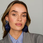 Navy feather drop earrings with ornate floral-inspired tops and gold-tone details on model head on