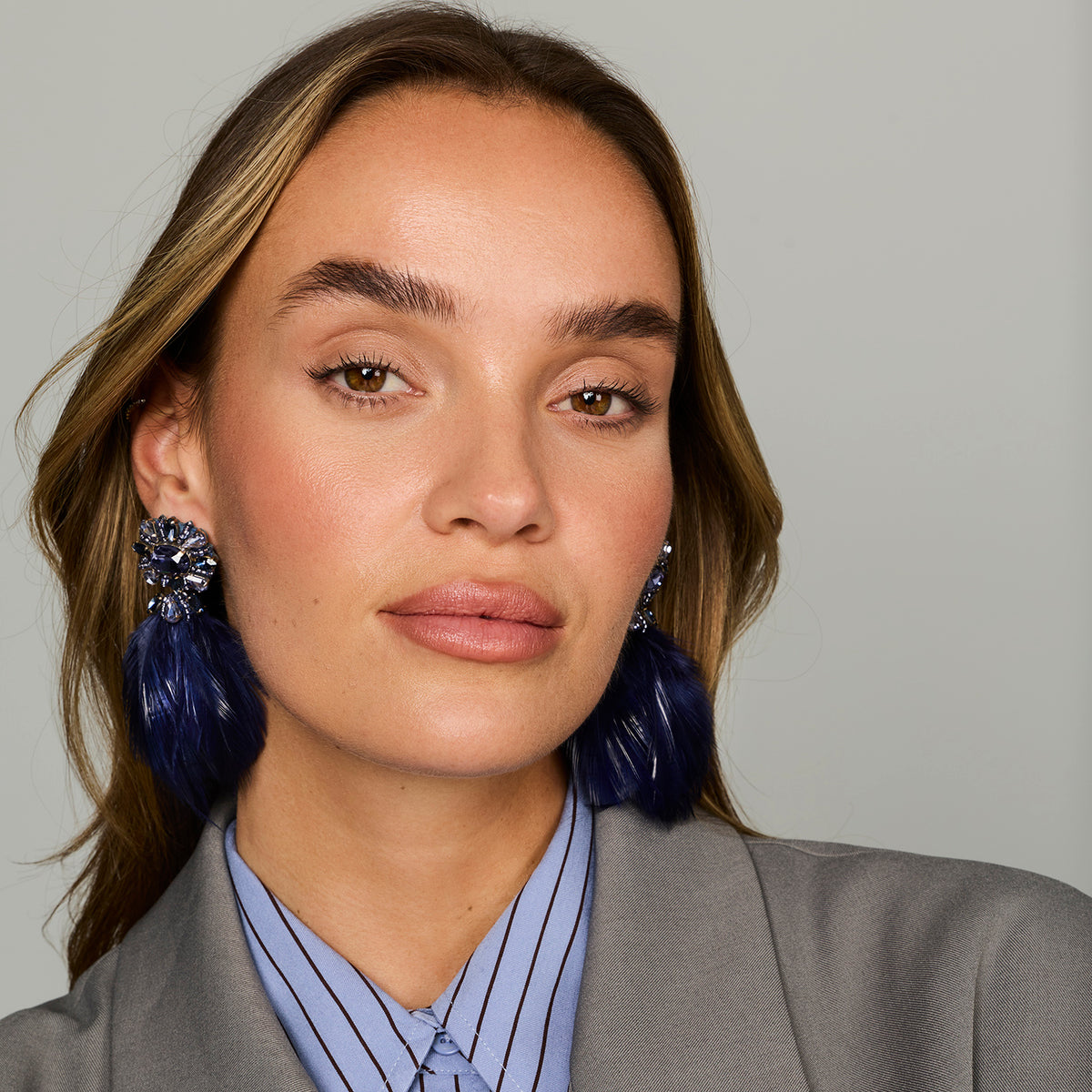 Navy feather drop earrings with ornate floral-inspired tops and gold-tone details on model head on