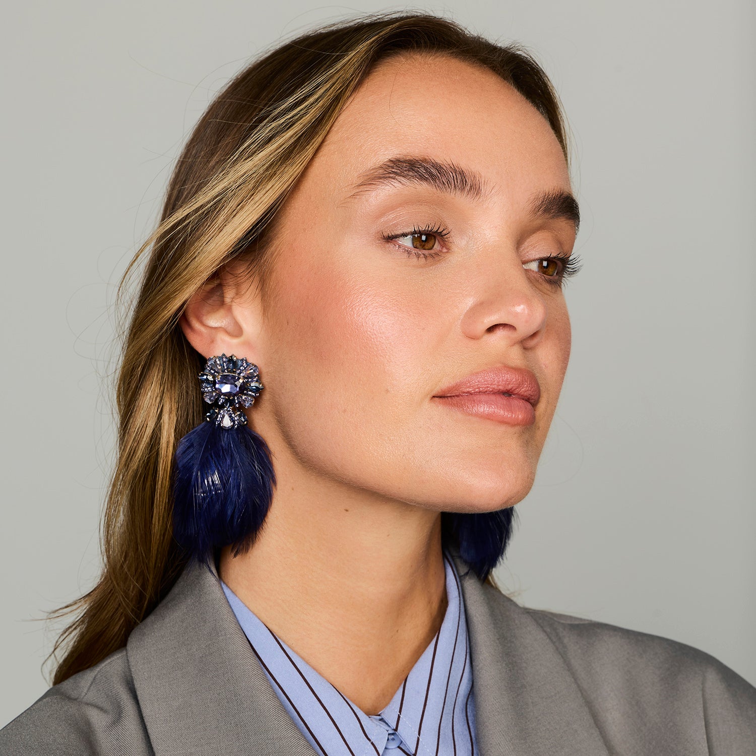 Navy feather drop earrings with ornate floral-inspired tops and gold-tone details on close up