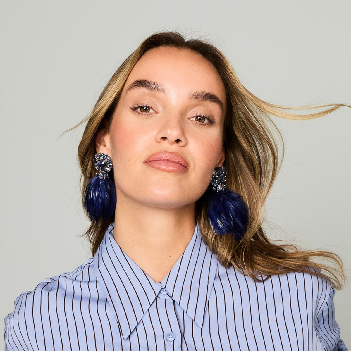 Navy feather drop earrings with ornate floral-inspired tops and gold-tone details on head titled up 