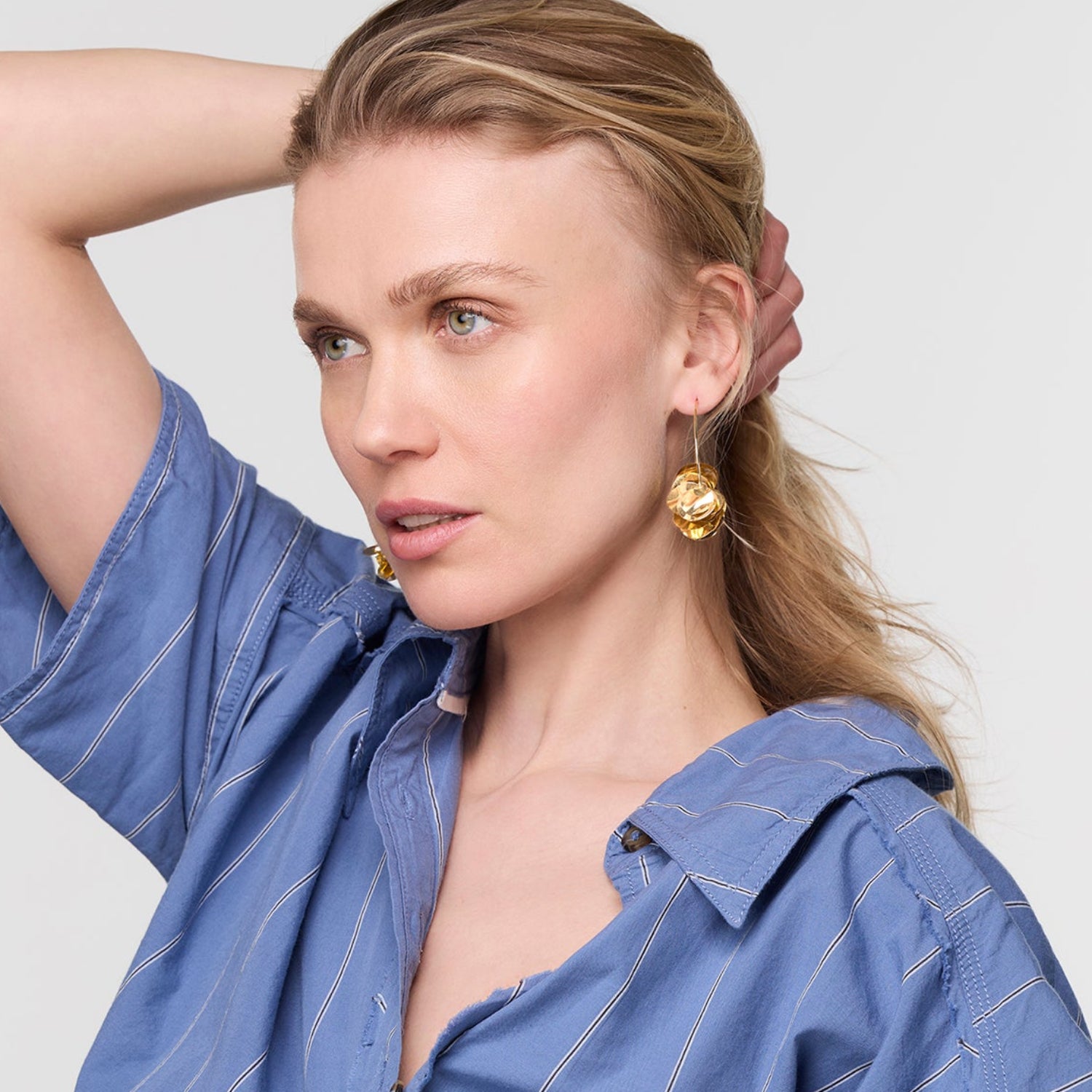 Woman wearing a blue striped shirt with a plain background