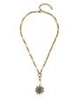 A gold chain necklace featuring a central gold-toned flower-like setting with a round green gemstone and small clear accent stones, displayed on a clean white background.