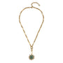 A gold chain necklace featuring a central gold-toned flower-like setting with a round green gemstone and small clear accent stones, displayed on a clean white background.
