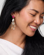 Close-up of a woman wearing a decorative earring with a red gemstone on a white background