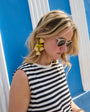 Model wearing yellow and pink tulip shaped earrings on blue background
