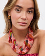 Woman wearing a colorful necklace and pink patterned dress against a white background