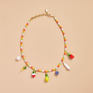 Beaded Charm Necklace with Fruit Charms and Pearls Styled on Cream Background