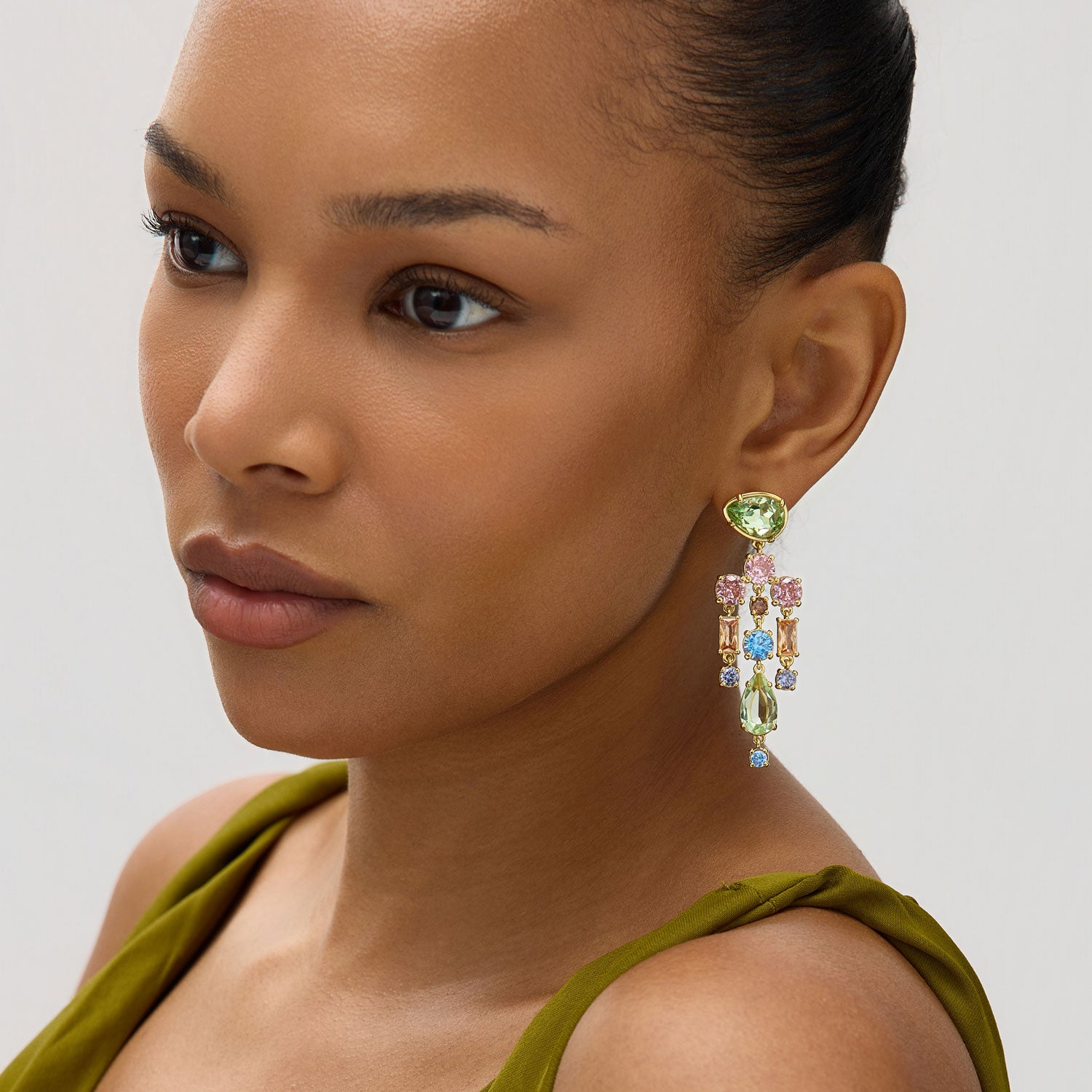Close-up of a woman wearing a colorful earring against a neutral background