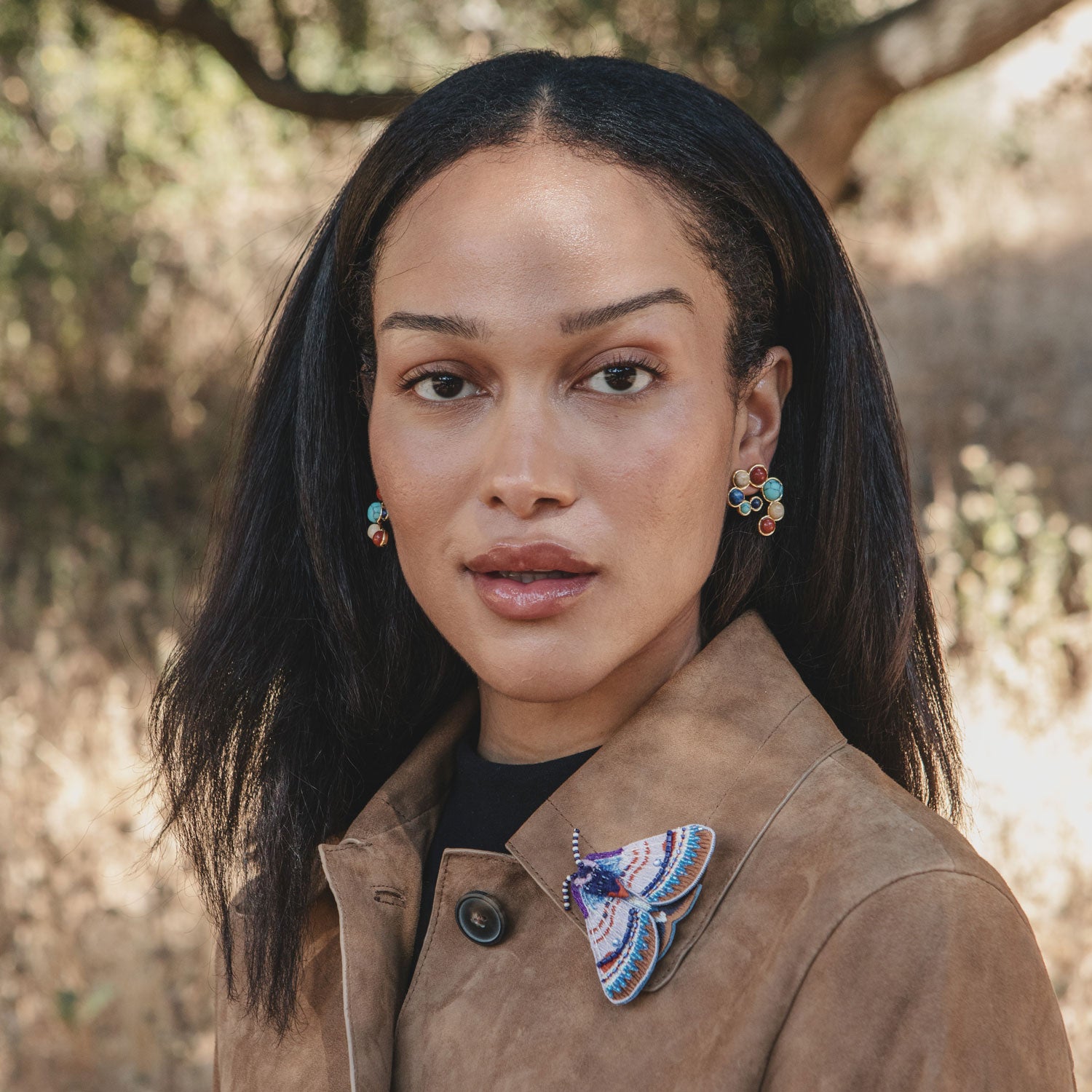 Pair of earrings with semi-precious stones styled on model with purple moth brooch