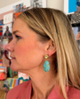 Woman wearing turquoise earrings in a colorful store setting