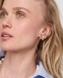 Close-up of a woman wearing gold Nicola Studs and a pearl necklace against a white background