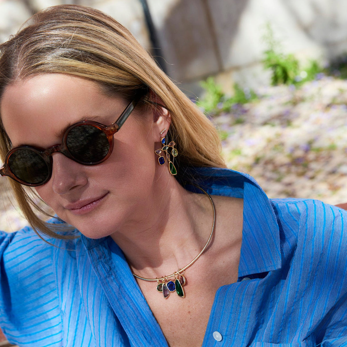 Gold-tone necklace featuring colorful green, blue, and clear pendants along a delicate chain on Mignonne Gavigan Lifestyle