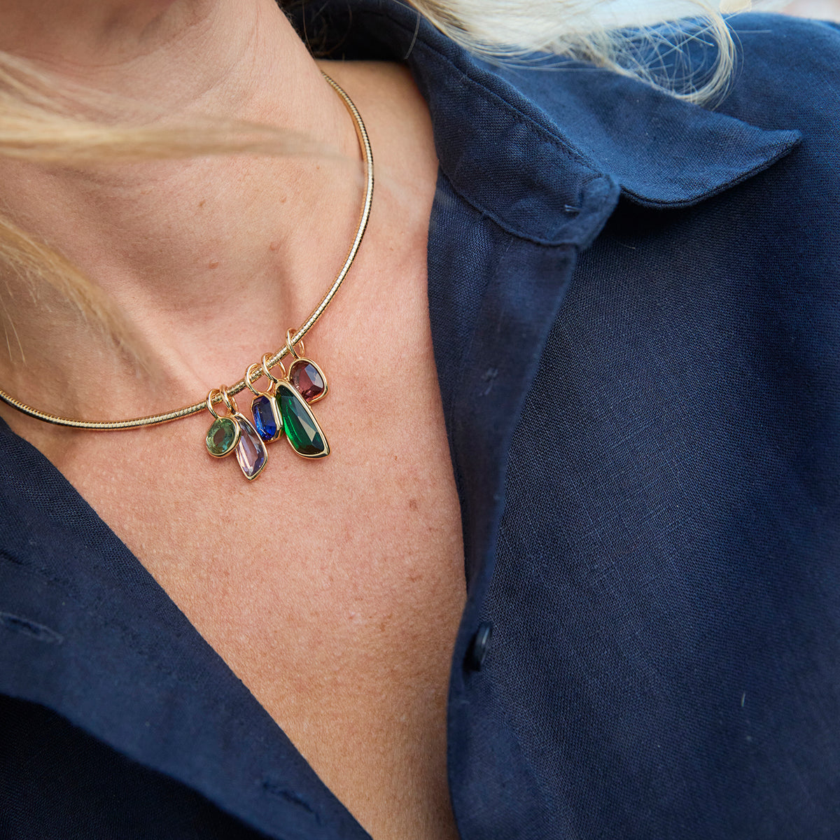 Gold-tone necklace featuring colorful green, blue, and clear pendants along a delicate chain on Mignonne Gavigan closeup
